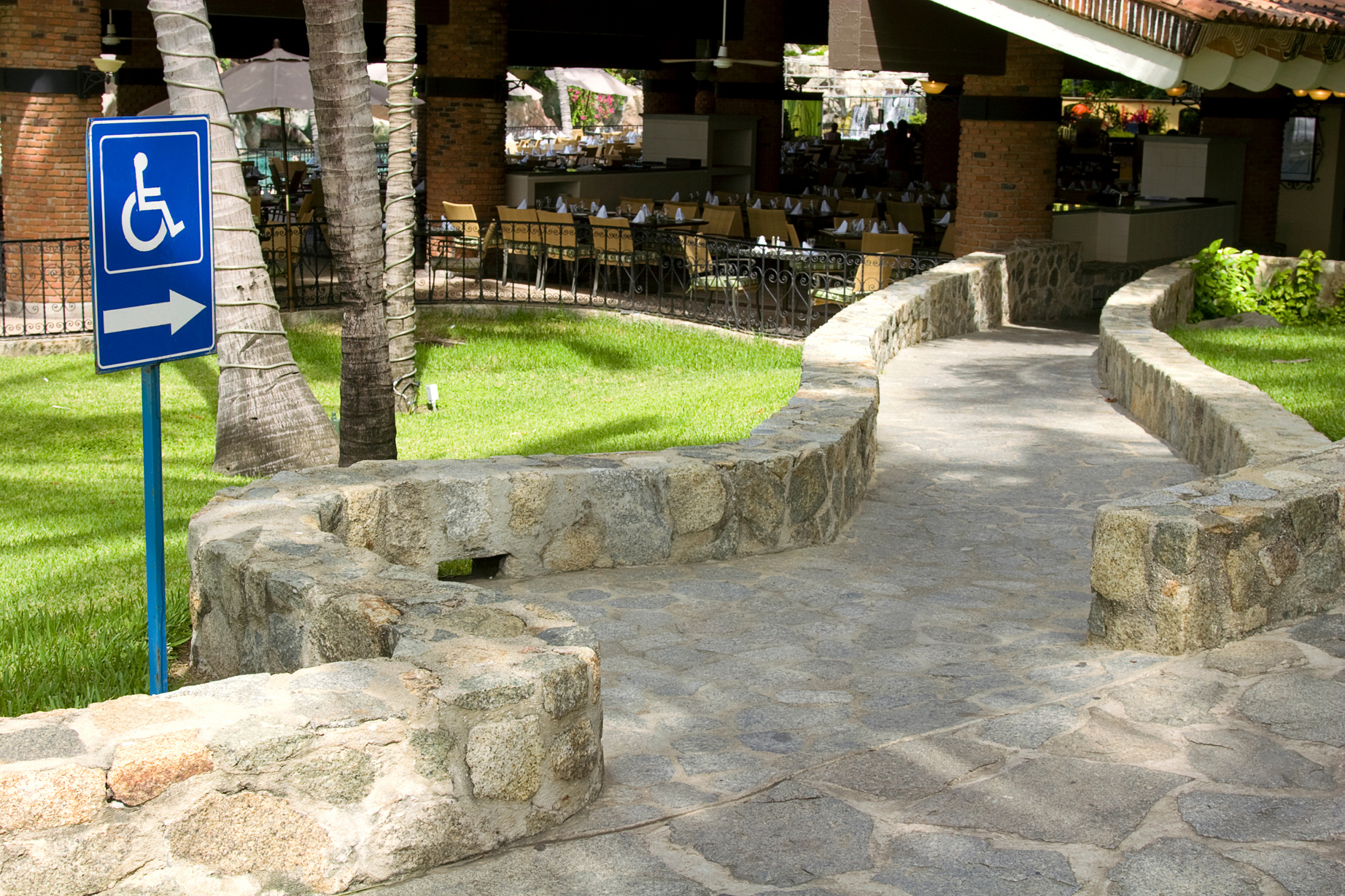 a pathway with a wheelchair accessible blue sign in front of an event space. white type on blue background and "contact us here" button overlay.